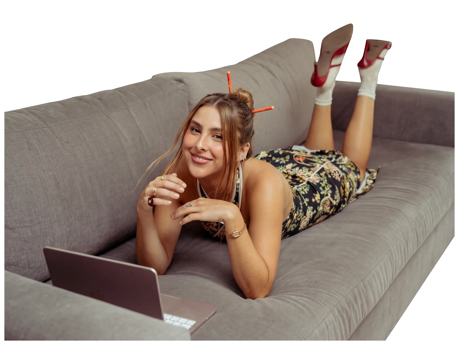 Maca acostada en el sillón con su laptop, sonriendo
