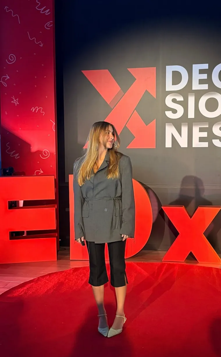 Maca en el escenario de TEDx, frente a las letras rojas